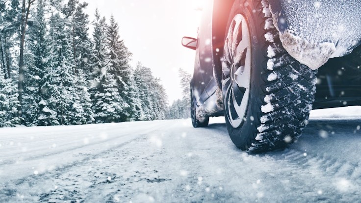 Auto mit Winterreifen in winterlicher Landschaft